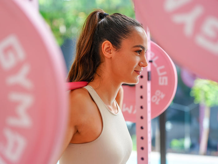 Gym Plus Cerakote Olympic Barbell - 15KG (Pink) GP-DOM-PINK-15KG woman smiling while weight lifting