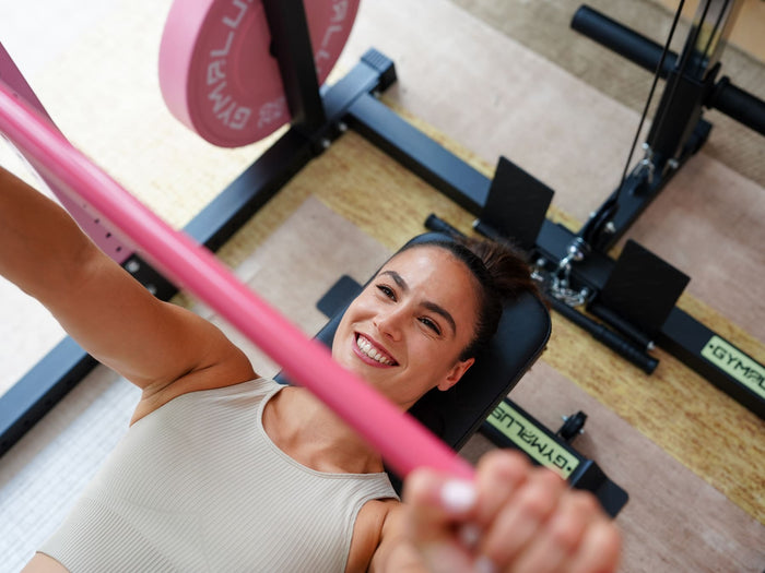 Gym Plus Cerakote Olympic Barbell - 15KG (Pink) GP-DOM-PINK-15KG woman smiling while performing weight lifting with pink bumper plates